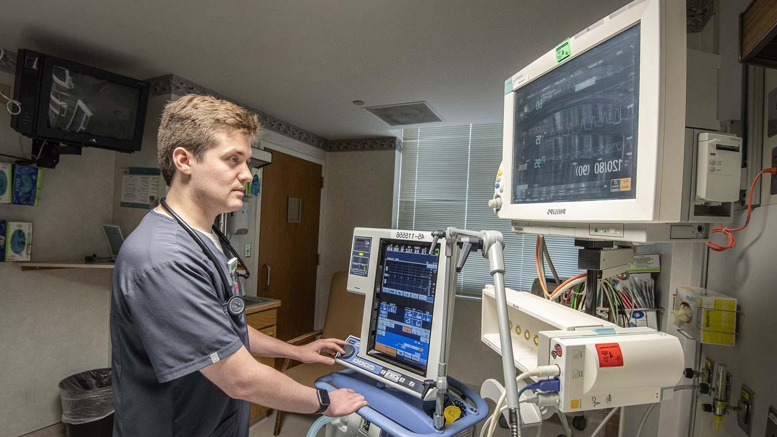 Male respiratory therapy student monitoring vitals of patient